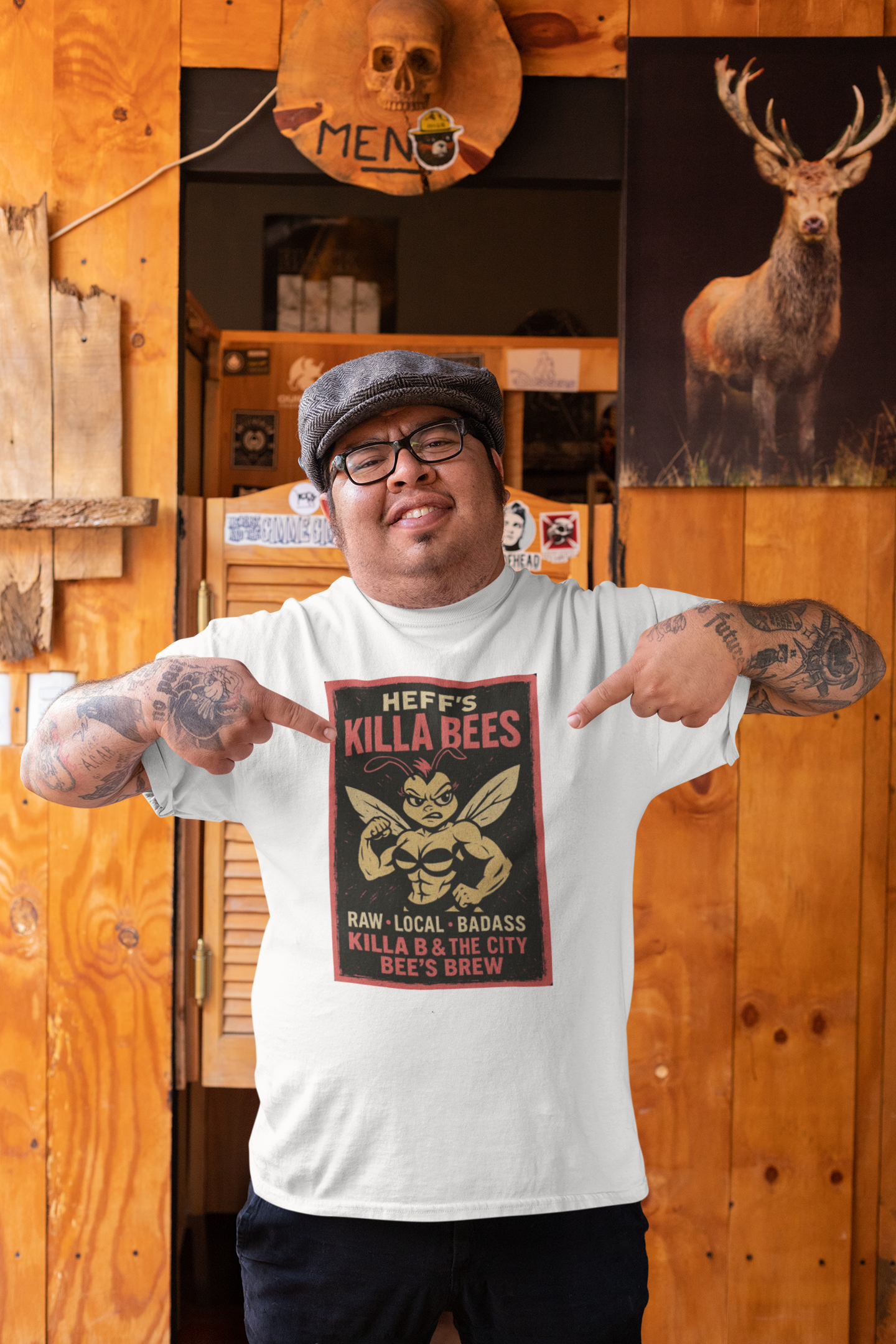 Man wearing a white t-shirt with a graphic design, standing in front of a wooden wall with a deer poster.