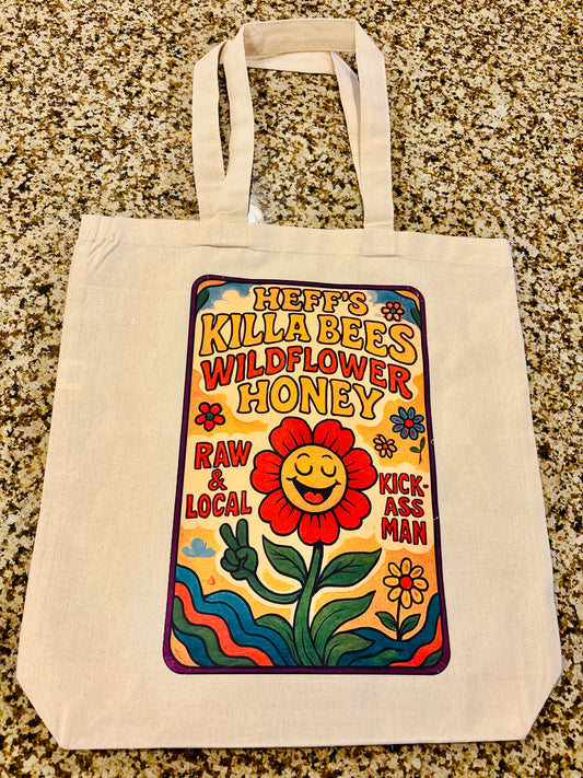 Tote bag with a colorful wildflower honey bee design featuring text and a flower on a textured surface.