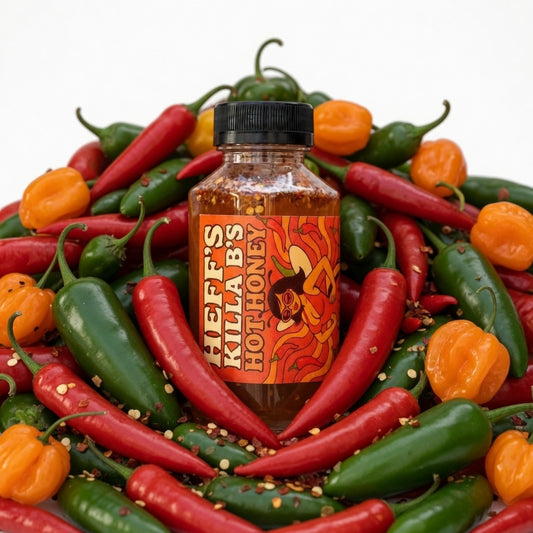Bottle of Heff's Killa Bees Hot Honey surrounded by colorful chili peppers on a white background